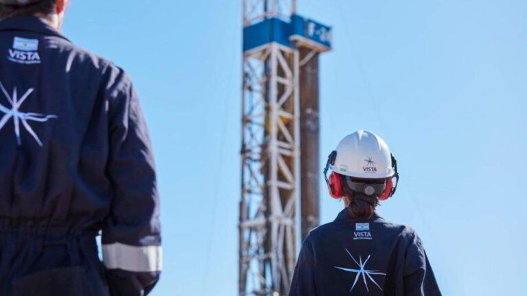 Trabajadores de la industria petrolera con equipo de seguridad observan una torre de perforación bajo un cielo despejado, con el logo de "Vista" visible en sus uniformes y cascos. Trabajadores de la industria petrolera con equipo de seguridad observan una torre de perforación bajo un cielo despejado, con el logo de "Vista" visible en sus uniformes y cascos.