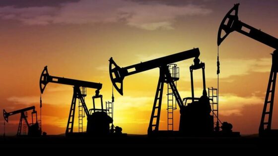 La imagen muestra cuatro pozos petrolíferos recortados contra el fondo del atardecer.