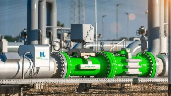 La imagen muestra una tubería industrial de color verde, etiquetada con 'H₂', que transporta hidrógeno. Se aprecian válvulas y sensores en la tubería, lo que sugiere un sistema de control y medición del flujo de hidrógeno.