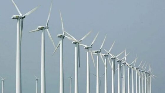 Una línea de molinos de energía eólica con un fondo de un cielo celeste.