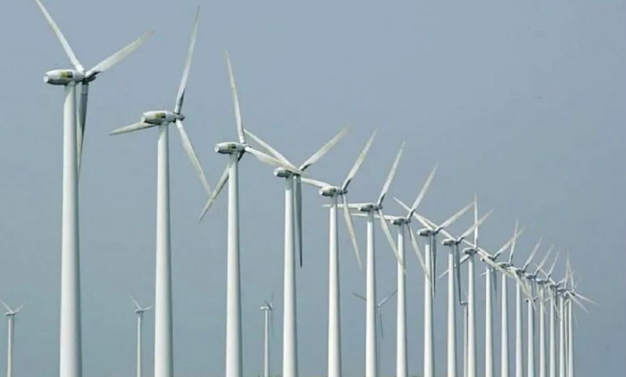 Una línea de molinos de energía eólica con un fondo de un cielo celeste.