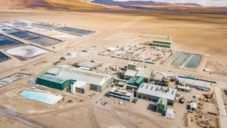 Vista aérea de una planta industrial en un paisaje ?rido con montañas al fondo. Se observan piscinas de evaporación de litio, edificios de procesamiento y maquinaria pesada.