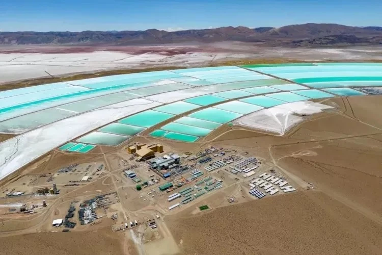 Vista aérea de un proyecto de extracción de litio en el Salar del Hombre Muerto, con piletas de evaporación de color turquesa y una planta industrial en el desierto, rodeada de montañas y salares.
