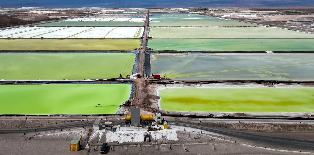Vista aérea de piscinas de evaporación en una planta de producción de litio en el norte argentino, con tonalidades verdes y amarillas en un paisaje desértico.
