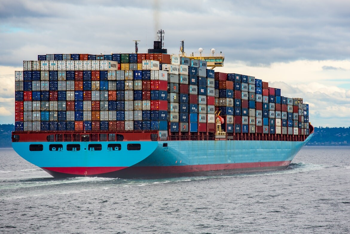 Barco portacontenedores navegando en mar abierto, emitiendo una densa columna de humo negro desde su chimenea.