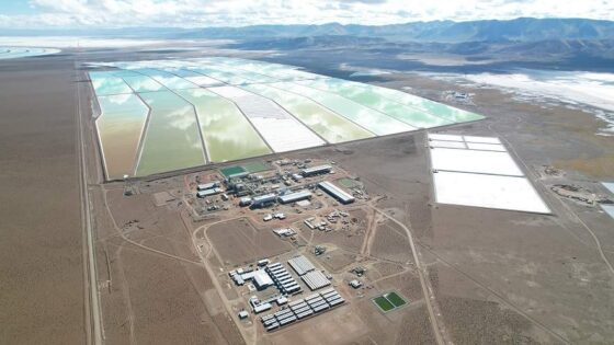 Vista aérea de una planta de extracción de litio en el Salar del Hombre Muerto, Argentina, operada por Ganfeng Lithium. En primer plano se observa el complejo industrial con instalaciones de procesamiento, mientras que al fondo se extienden grandes piletones de evaporación de salmuera, cuyos colores varían según el grado de concentración de litio.