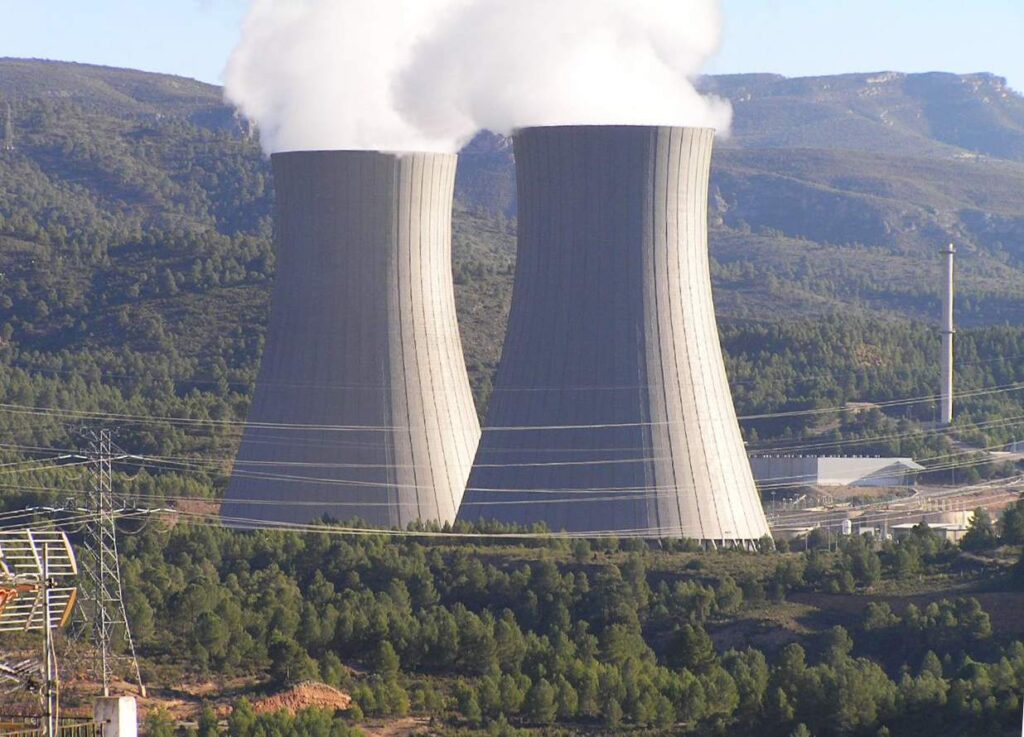 Torres de refrigeración de una central nuclear rodeadas de un paisaje monta?oso y boscoso. Las estructuras liberan vapor de agua al cielo.