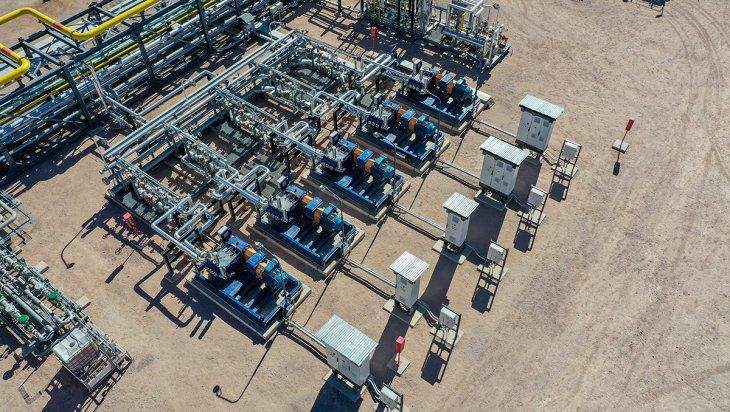 Imagen aérea de una wellpad. Se ve un conjunto de cabezales de pozo interconectados por una red densa de tuberías y equipos de bombeo.