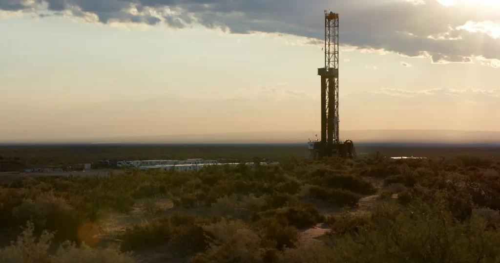 Plataforma petrolera en Vaca Muerta, Argentina, bajo un cielo nublado al atardecer.