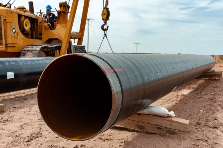 Tubo de gran di?metro para oleoducto en proceso de instalación sobre soportes de madera en un terreno ?rido.