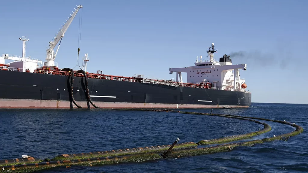 Buque petrolero amarrado en alta mar, conectado mediante mangueras flotantes para carga o descarga de crudo.