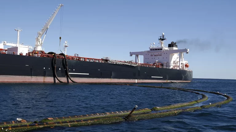Buque petrolero amarrado en alta mar, conectado mediante mangueras flotantes para carga o descarga de crudo.
