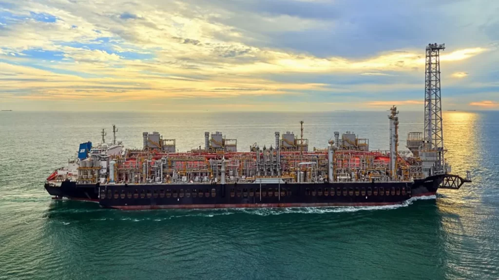 Buque de producción y procesamiento de gas natural licuado (GNL) navegando en mar abierto al atardecer.