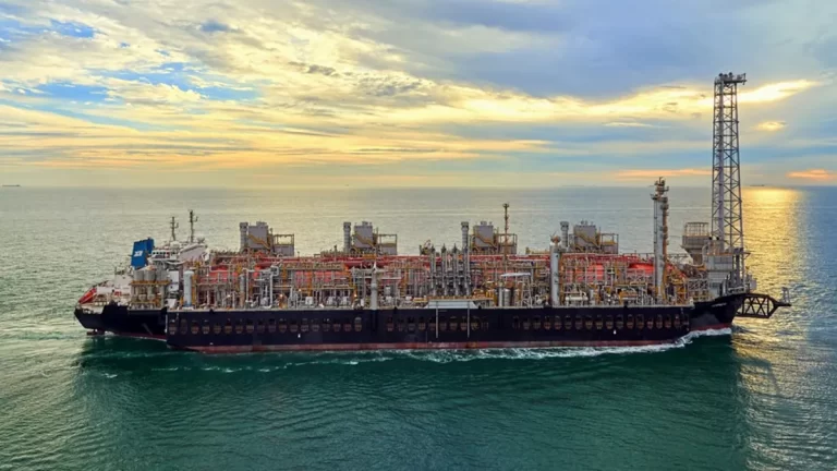 Buque de producción y procesamiento de gas natural licuado (GNL) navegando en mar abierto al atardecer.