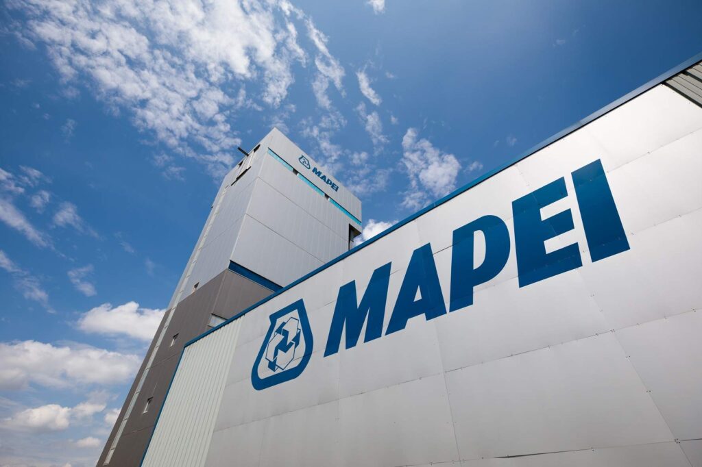 Edificio industrial de Mapei con su logo destacado en la fachada, bajo un cielo despejado.