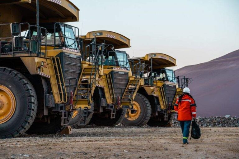 Trabajador de la miner?a frente a camiones de gran porte en una operación a cielo abierto.