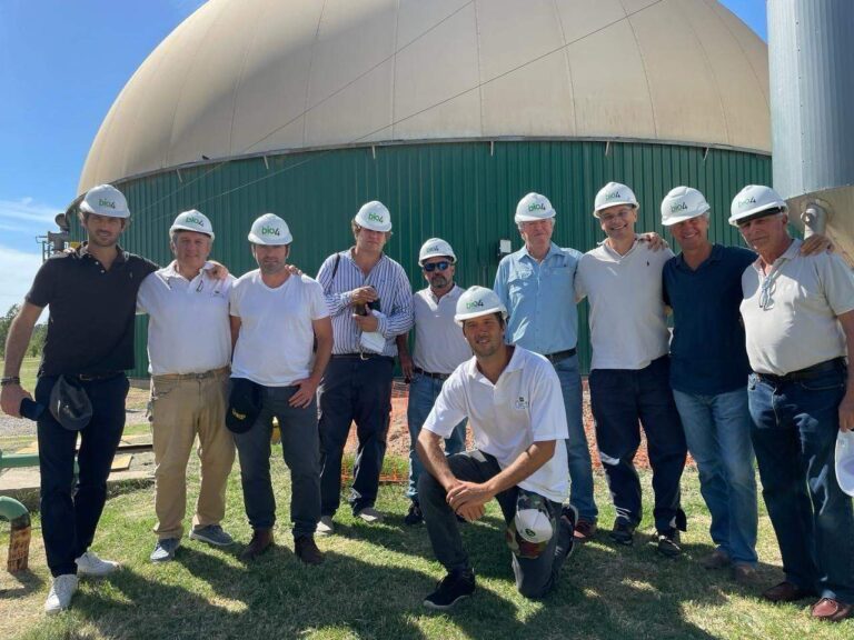 Grupo de personas con cascos de seguridad de la empresa Bio4, posando frente a una planta de bioenergía con estructura cilíndrica y cúpula.