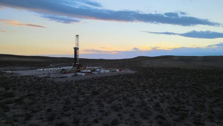 Plataforma de perforación petrolera en un paisaje ?rido durante el atardecer.