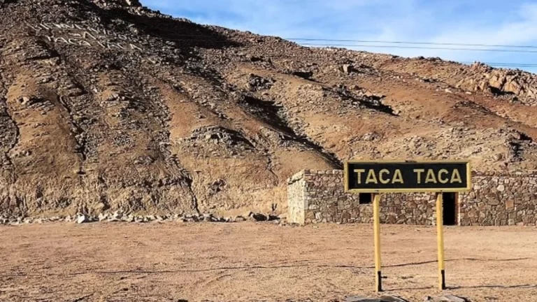 Se?al de carretera que indica "TACA TACA" con un paisaje monta?oso des?rtico de fondo.