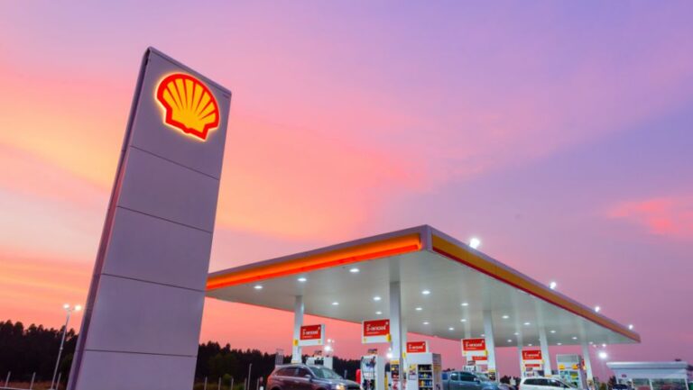 Estación de servicio Shell iluminada al atardecer.