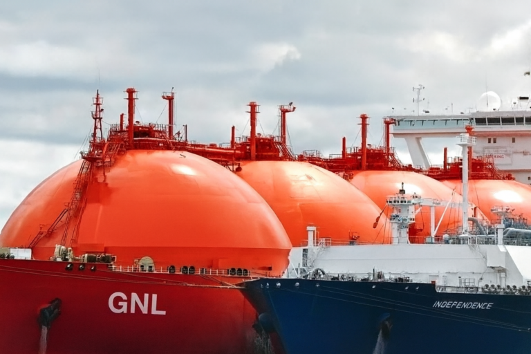 Buque metanero rojo con tanques esféricos de GNL durante una operación en el puerto.