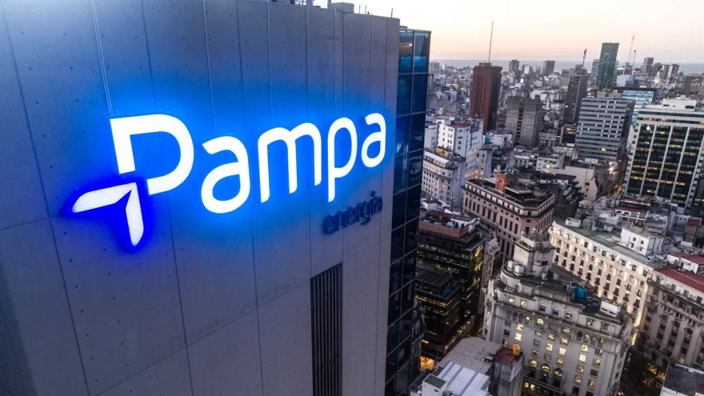 Edificio corporativo con el logo iluminado de Pampa Energ?a, con vista aérea del centro urbano al atardecer.