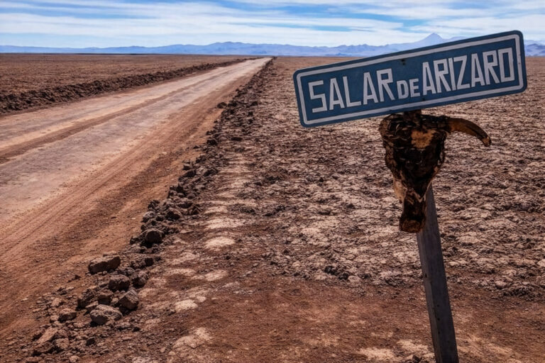 Camino de tierra en el Salar de Arizaro con cartel indicador en primer plano.