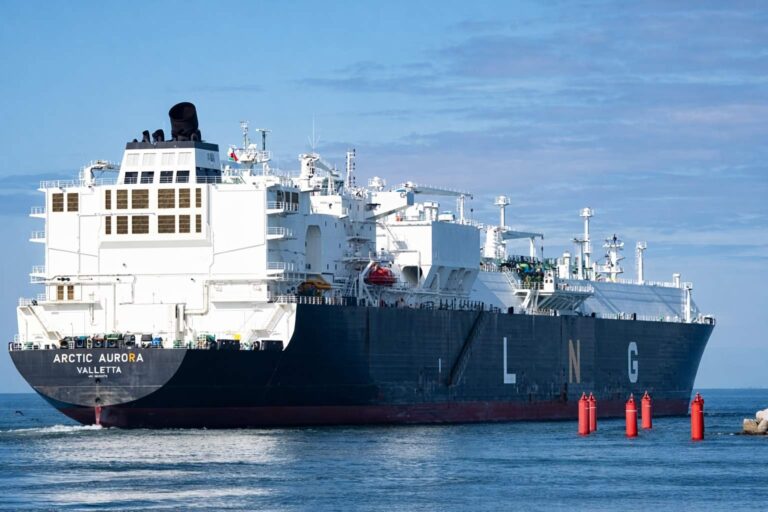 Buque metanero de gran tamaño transportando gas natural licuado (LNG), navegando en aguas costeras bajo cielo despejado.