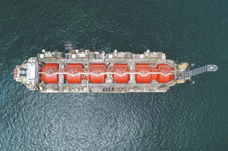 Vista aérea de un buque metanero con tanques de GNL de color rojo navegando en mar abierto.