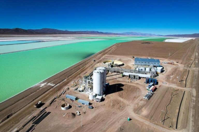 Vista aérea de una planta de procesamiento de litio junto a extensas piletas de evaporación en un salar de alta montaña.