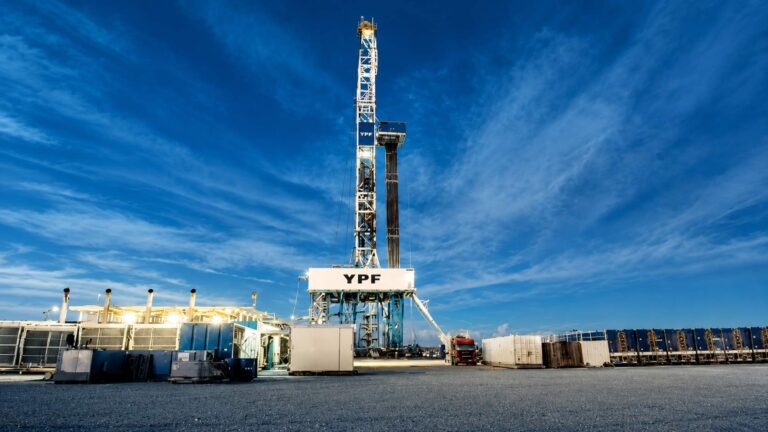 Torre de perforación de YPF en un yacimiento petrolero, rodeada de equipos industriales y contenedores bajo un cielo despejado.