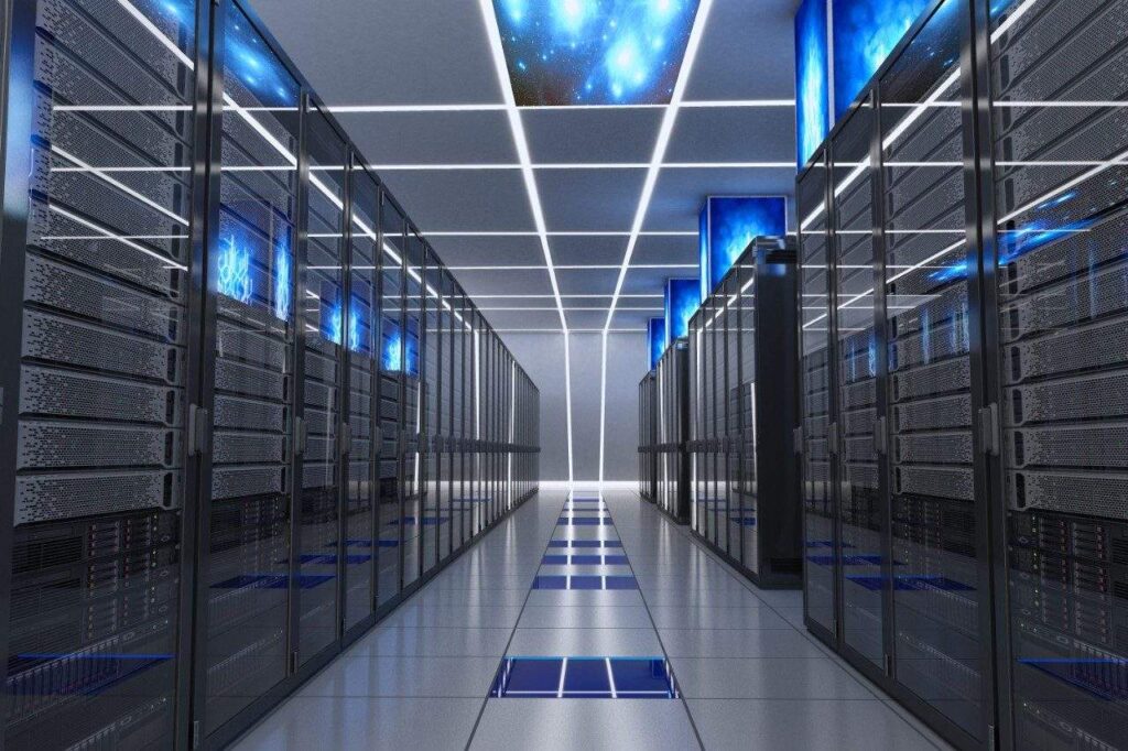 Pasillo de un centro de datos con filas de servidores alojados en racks, iluminación LED y equipos informáticos destinados al procesamiento y almacenamiento de información digital.
