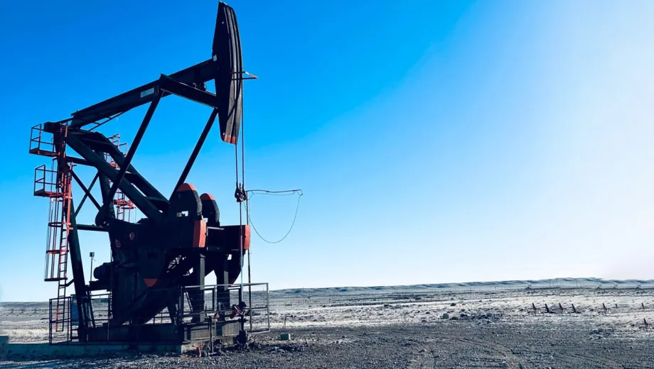 Equipo de bombeo mecánico de petróleo (pumpjack) operando en un yacimiento terrestre, sobre un terreno árido y abierto bajo un cielo despejado.