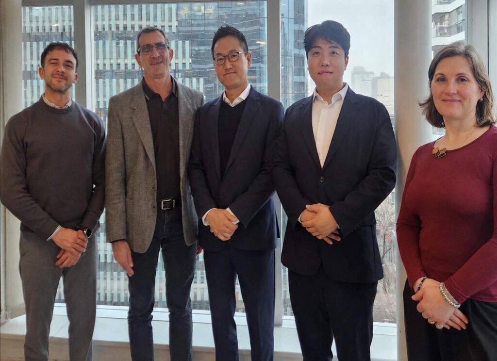Cinco representantes de empresas reunidos en una oficina durante un encuentro institucional, con ventanales y edificios de la ciudad de fondo.