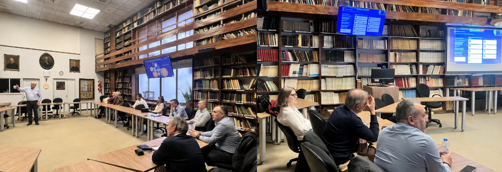 Participantes reunidos en una sala de biblioteca durante una presentación, con un expositor al frente y pantallas con información proyectada, en el marco de una reunión de trabajo.