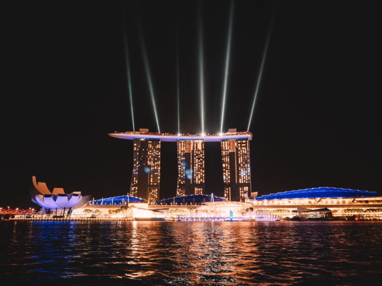 mpresionante vista nocturna de Marina Bay Sands con luces deslumbrantes reflejadas en el agua en Singapur.